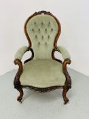 A VICTORIAN MAHOGANY SPOON BACK OPEN ARMCHAIR WITH BUTTON BACK AND GREEN VELOUR UPHOLSTERY