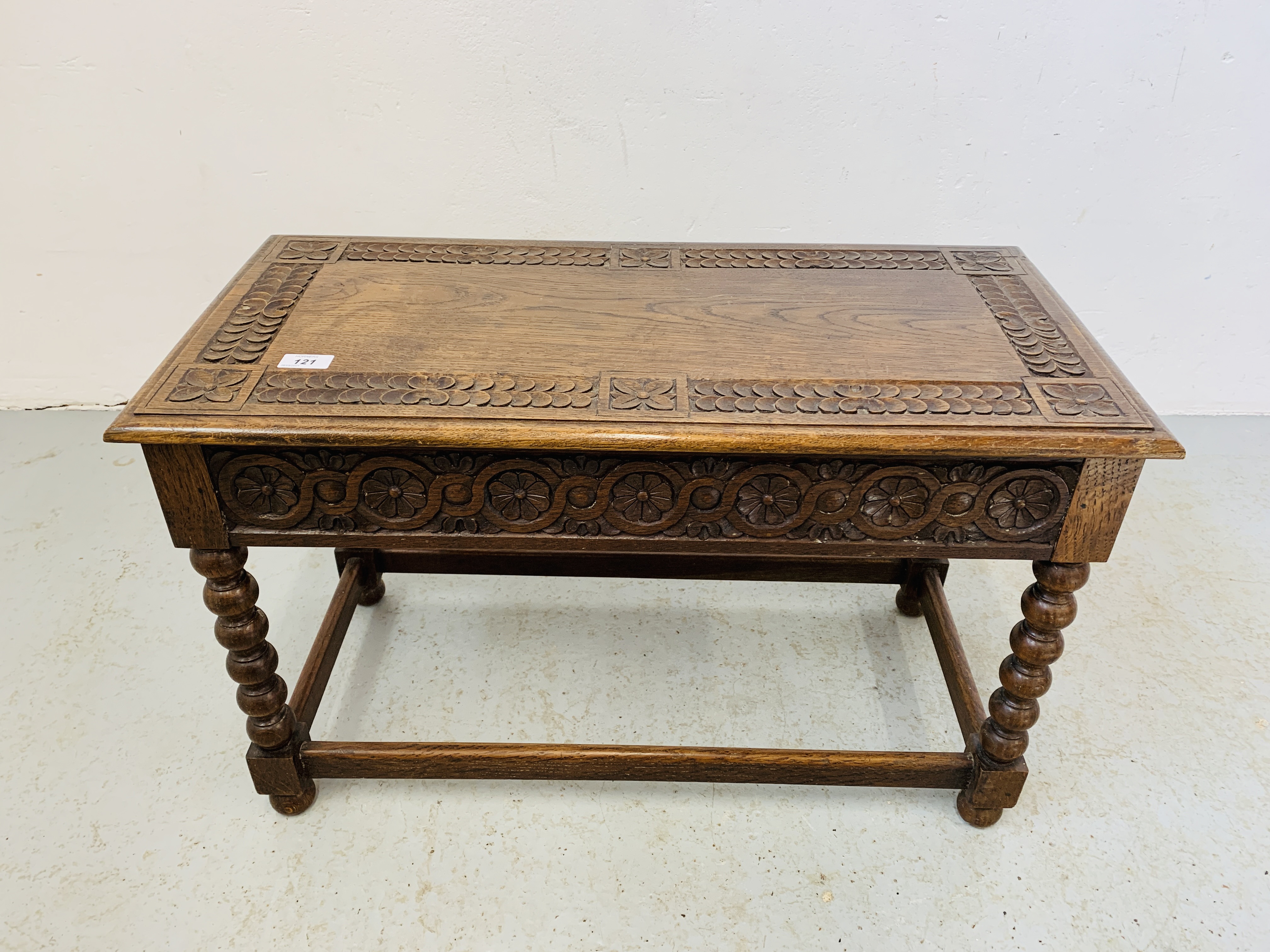 A HAND CARVED OAK SIDE TABLE WITH HINGED TOP AND BOBBIN DETAILED SUPPORTS - W 75CM. D 37CM. H 46CM.