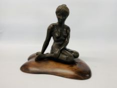 A BRONZED RESIN SCULPTURE OF A SEATED WOMAN BY SONIA DOBBS ON PINE BASE - HEIGHT 33.5 CM.