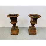 A PAIR OF CAST IRON TULIP SHAPE GARDEN URNS ON STANDS A/F CONDITION - OVERALL HEIGHT 68CM.