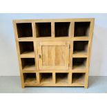 A HARDWOOD ACACIA PIGEON HOLE DISPLAY CABINET WITH CENTRAL CUPBOARD - W 135CM. D 45CM. H 135CM.
