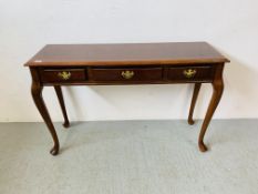 A REPRODUCTION MAHOGANY FINISH THREE DRAWER SIDE TABLE ON QUEEN ANNE STYLE LEG W 121CM, D 40CM,