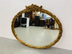 A LARGE OVAL GILT DECORATED WALL MIRROR - WIDTH 127CM. HEIGHT 110CM.