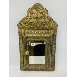 AN EMBOSSED BRASS CUSHION MIRROR WITH HINGED DOOR CONTAINING CLOTHES BRUSHES