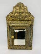 AN EMBOSSED BRASS CUSHION MIRROR WITH HINGED DOOR CONTAINING CLOTHES BRUSHES