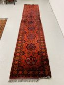 A RED PATTERNED PERSIAN HALL RUNNER 385CM X 80CM