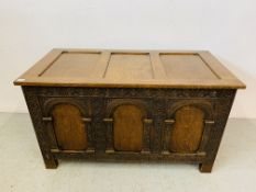 AN OAK BLANKET BOX WITH HEAVILY CARVED 3 PANEL FRONT