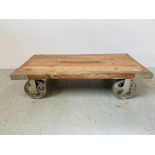 A RUSTIC LOW LEVEL HARDWOOD COFFEE TABLE/STAND ON OVER SIZE INDUSTRIAL STYLE CASTORS