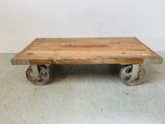 A RUSTIC LOW LEVEL HARDWOOD COFFEE TABLE/STAND ON OVER SIZE INDUSTRIAL STYLE CASTORS