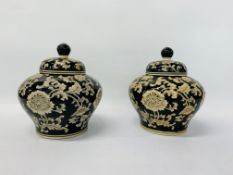 A PAIR OF COVERED VASES THE CREAM DECORATION ON A BLACK GROUND HEIGHT 23CM