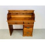 A HONEY PINE SINGLE PEDESTAL ROLL TOP DESK (THE TAMBER REQUIRING SOME REFINISHING) - W 105CM.