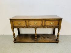 A GOOD QUALITY REPRO 3 DRAWER OAK BUFFET WITH CARVED FRIEZE + TURNED SUPPORTS - W 141CM. D 47CM.