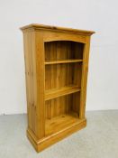 A SOLID HONEY PINE BOOKSHELF WITH TONGUE AND GROOVE BOARDED BACK - W 66CM. D 26CM. H 107CM.