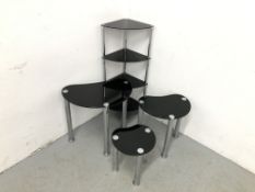 A NEST OF THREE GRADUATED RETRO STYLE BLACK GLASS AND CHROME OCCASIONAL TABLES + FOUR TIER CORNER