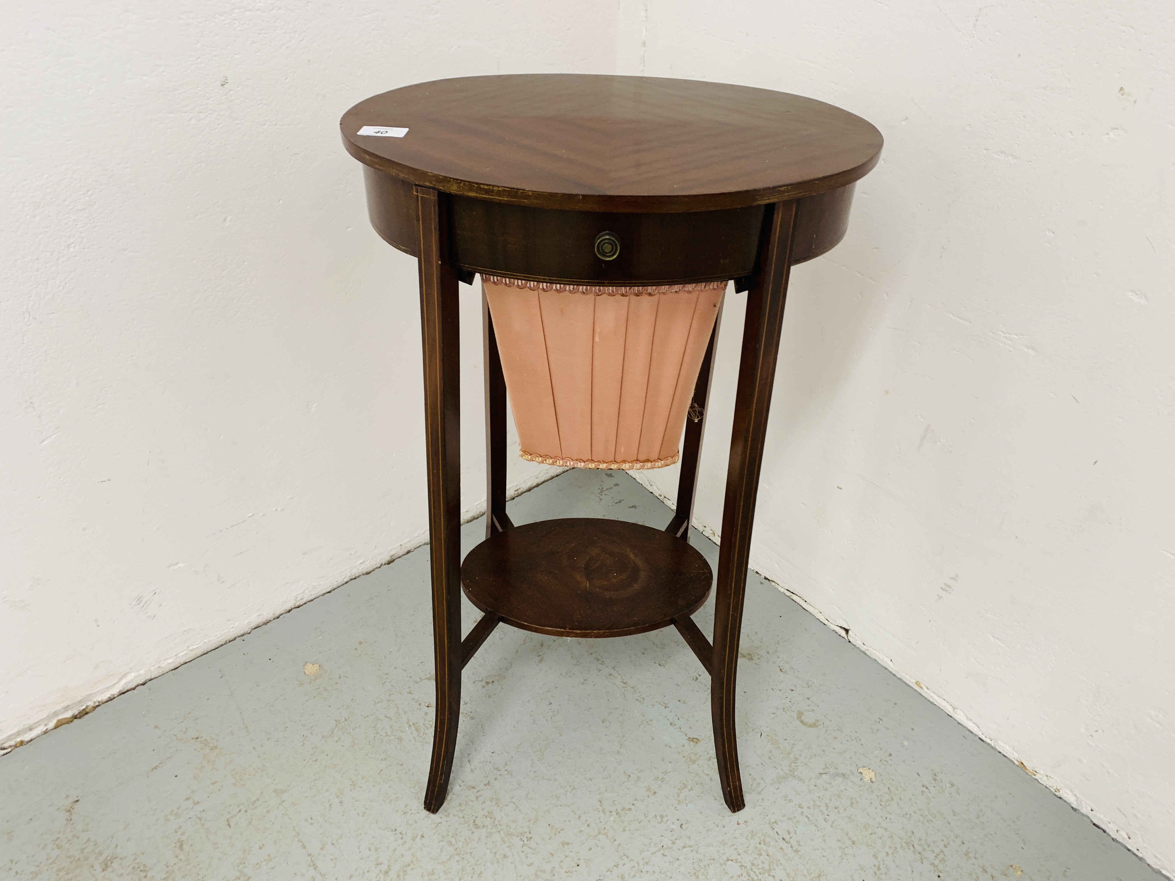 AN EDWARDIAN MAHOGANY TWO TIER WORK TABLE OF OVAL FORM ON SPLAYED LEG,
