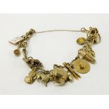 A 9CT GOLD CHARM BRACELET WITH TWELVE CHARMS ATTACHED