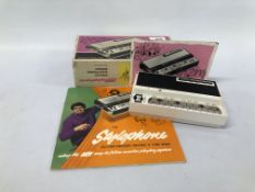 A BOXED POCKET "STYLOPHONE" ALONG WITH THE STYLOPHONE ACCOMPANIMENT RECORD AND TUNE BOOK