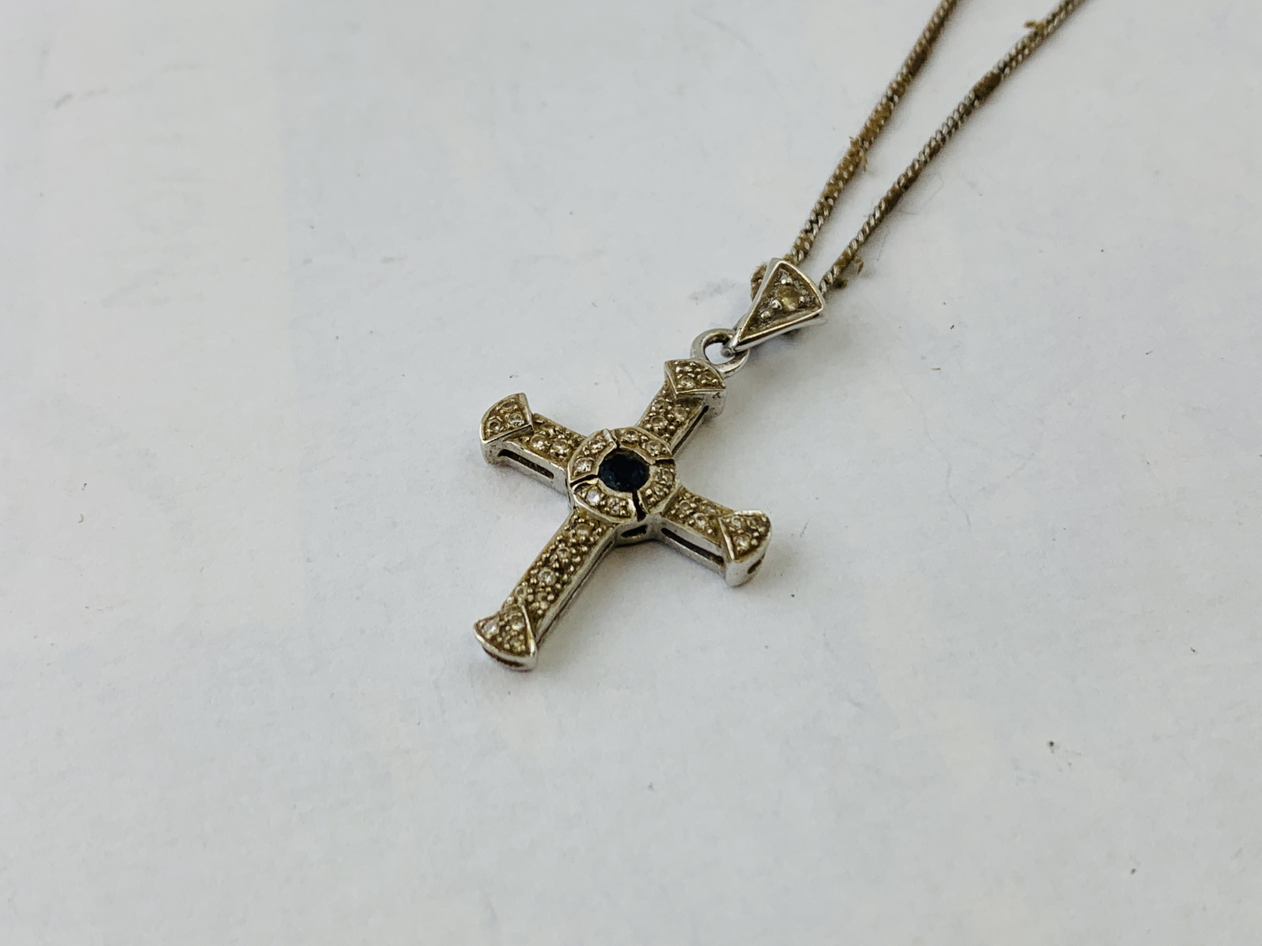 18CT WHITE GOLD PENDANT CROSS SET WITH CENTRAL SAPPHIRE AND SMALL DIAMOND SUSPENDED FROM A FINE