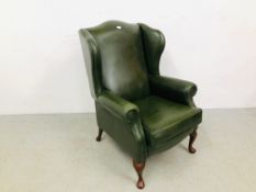 A MODERN BOTTLE GREEN LEATHER WINGED FIRESIDE CHAIR