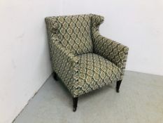 AN EDWARDIAN UPHOLSTERED WINGED EASY CHAIR