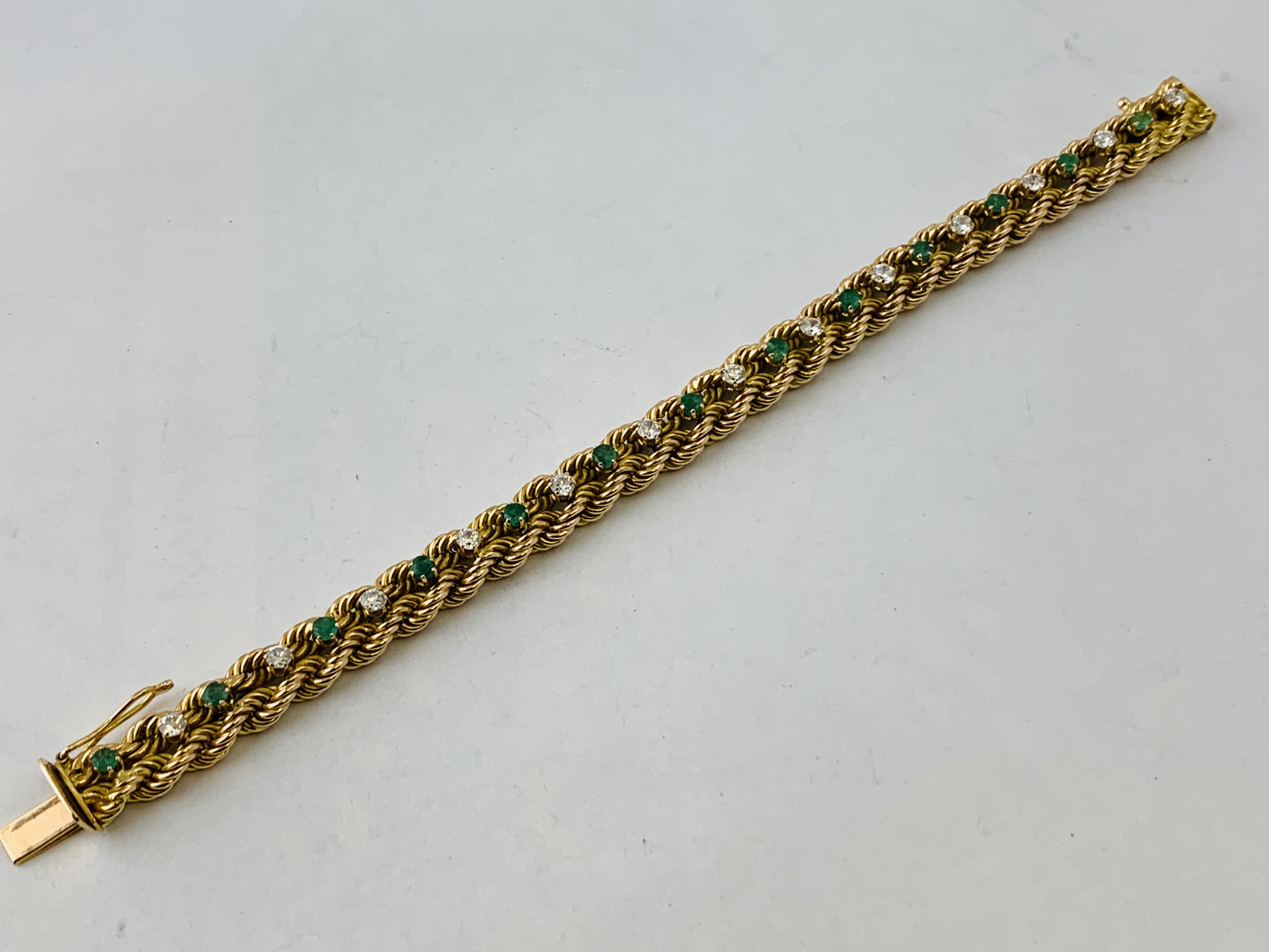 A BRAIDED DIAMOND AND EMERALD BRACELET MARKED 14K,