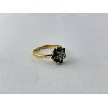 A DIAMOND AND GREEN STONE SET FLOWER HEAD RING (RUBBED MARKS)