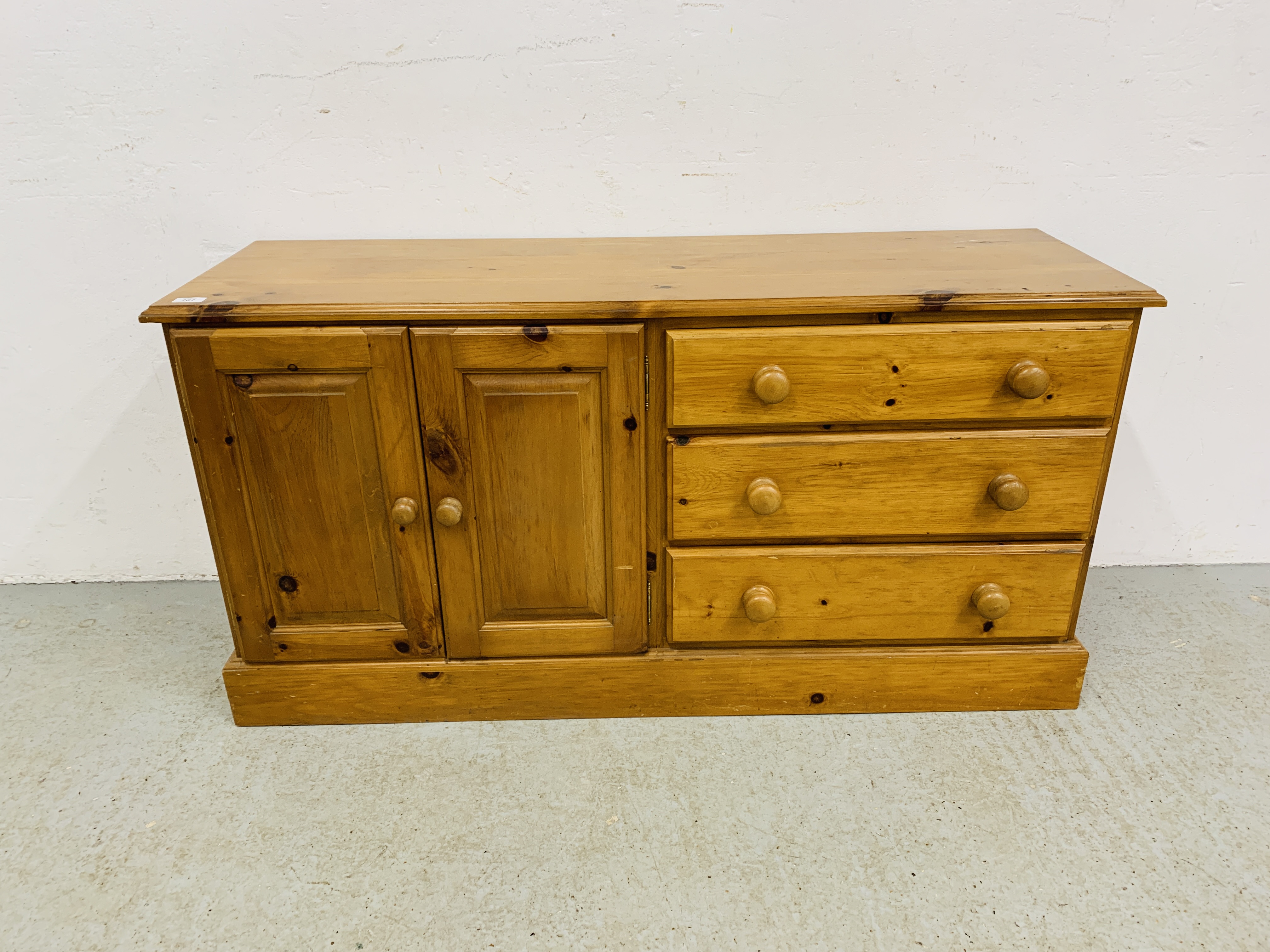 A SOLID HONEY PINE THREE DRAWER DRESSER BASE WITH CABINET TO ONE END - W 130CM. D 41CM. H 66CM.
