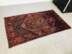 AN EASTERN RUG ON RED GROUND 205CM X 112CM