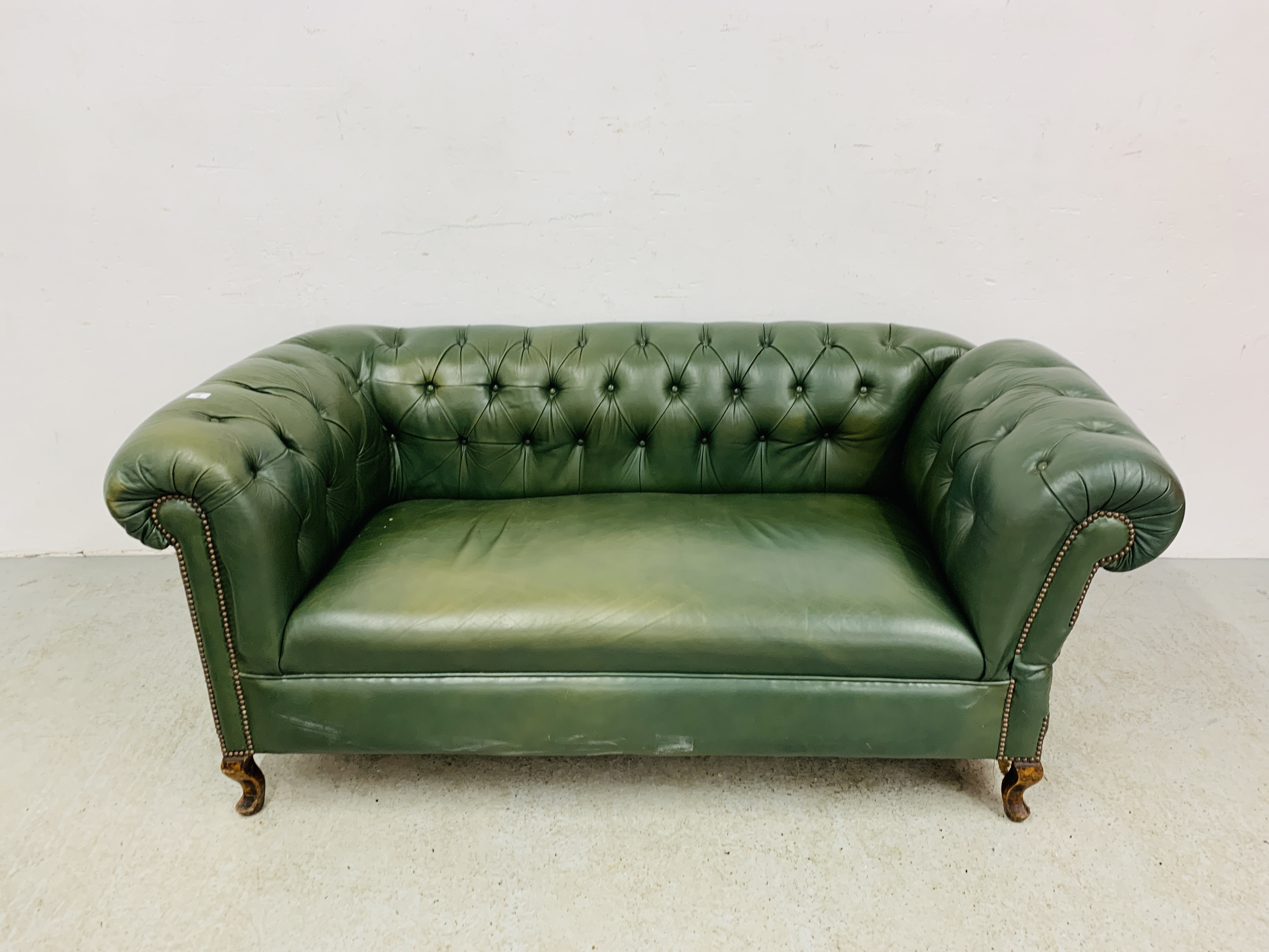 A GREEN LEATHER BUTTON BACK DROP END CHESTERFIELD STYLE SOFA WITH FOOT STOOL.