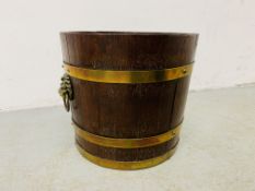 A BRASS BOUND OAK LOG BUCKET WITH LION HEAD RING PULL FITTINGS - DIAMETER 36CM. HEIGHT 33CM.