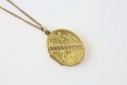 AN OVAL YELLOW METAL LOCKET WITH GRECIAN KEY AND FERN DESIGN, ON AN UNMARKED YELLOW METAL CHAIN,