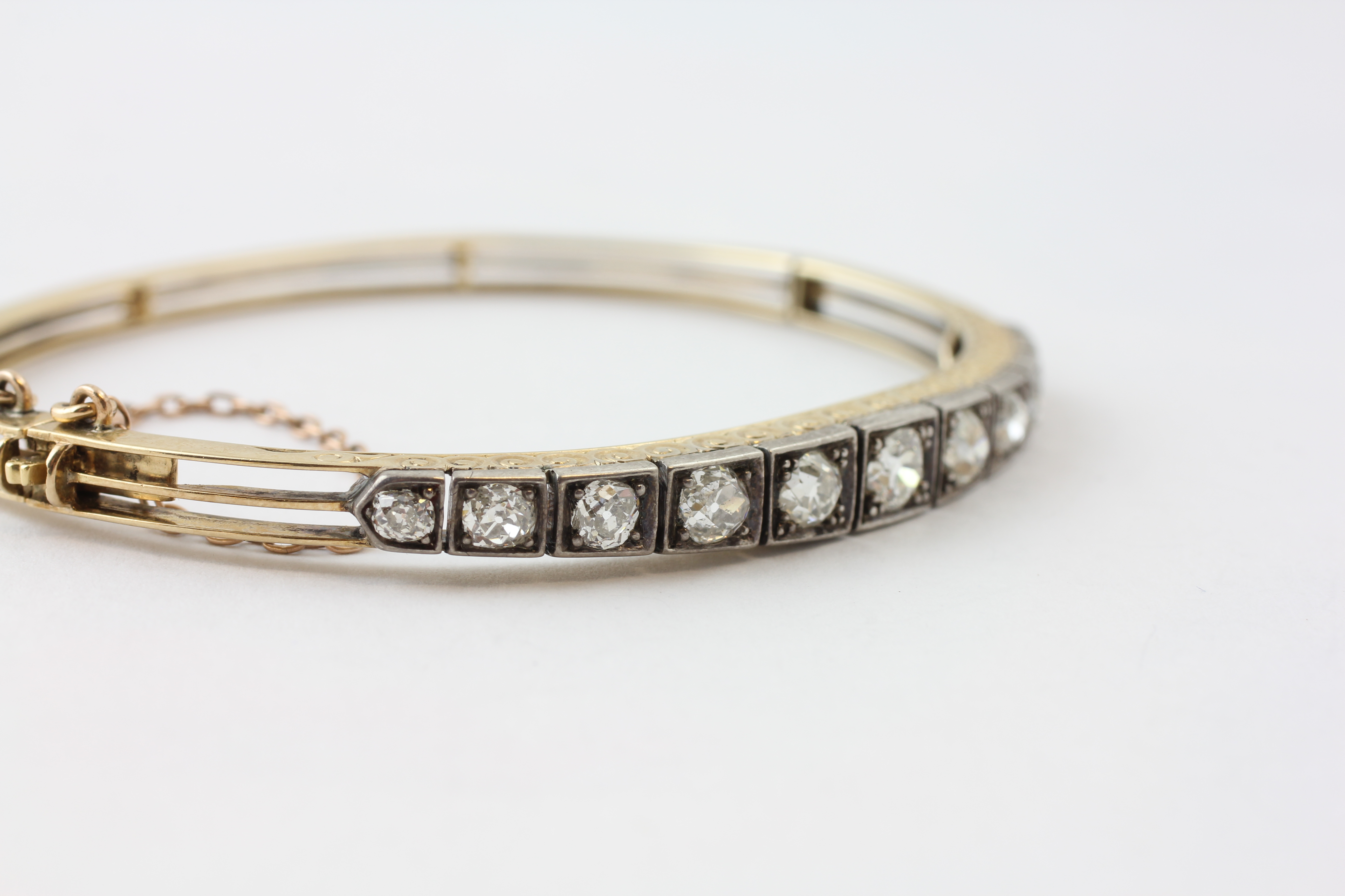 AN ELEVEN STONE DIAMOND HINGED BANGLE WITH SAFETY CHAIN, - Image 4 of 7