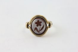 A CHALCEDONY SIGNET RING ENGRAVED WITH A FLOWER SET IN UNMARKED YELLOW METAL,