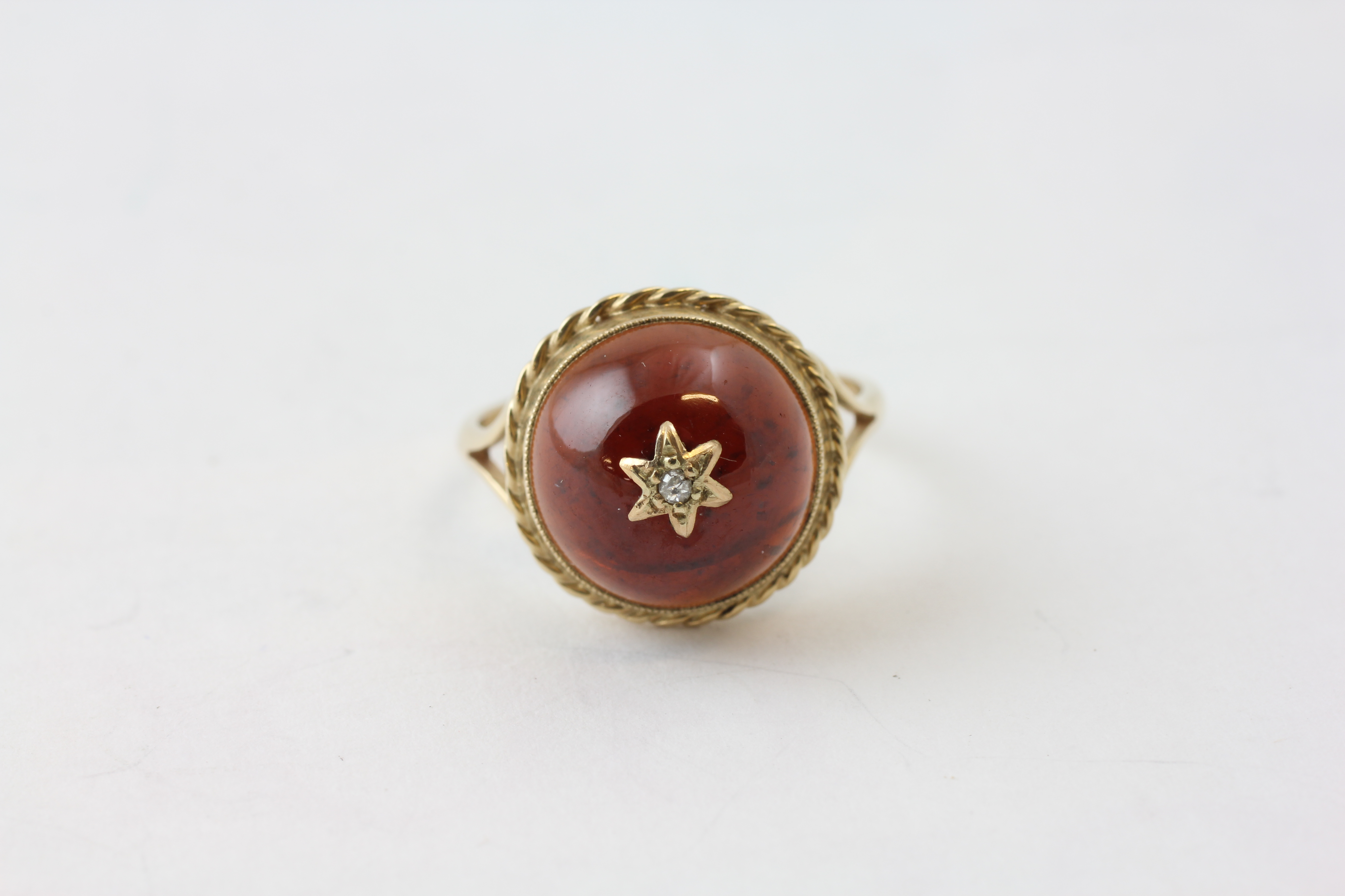 A 9CT GOLD RING SET WITH A PALE RED CABOCHON, MOUNTED WITH A DIAMOND,