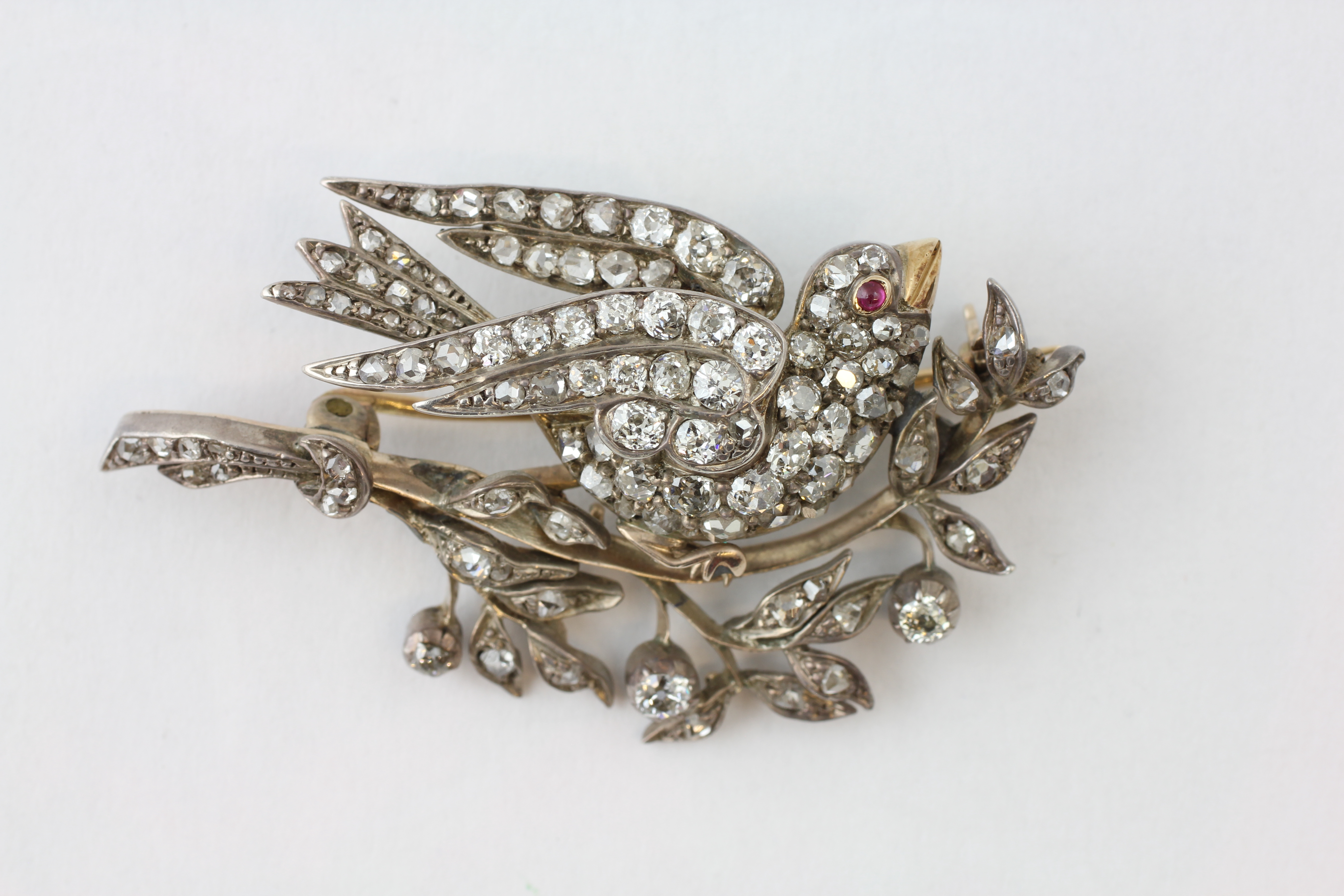 A BIRD BROOCH HAVING A RUBY EYE AND YELLOW METAL BEAK,