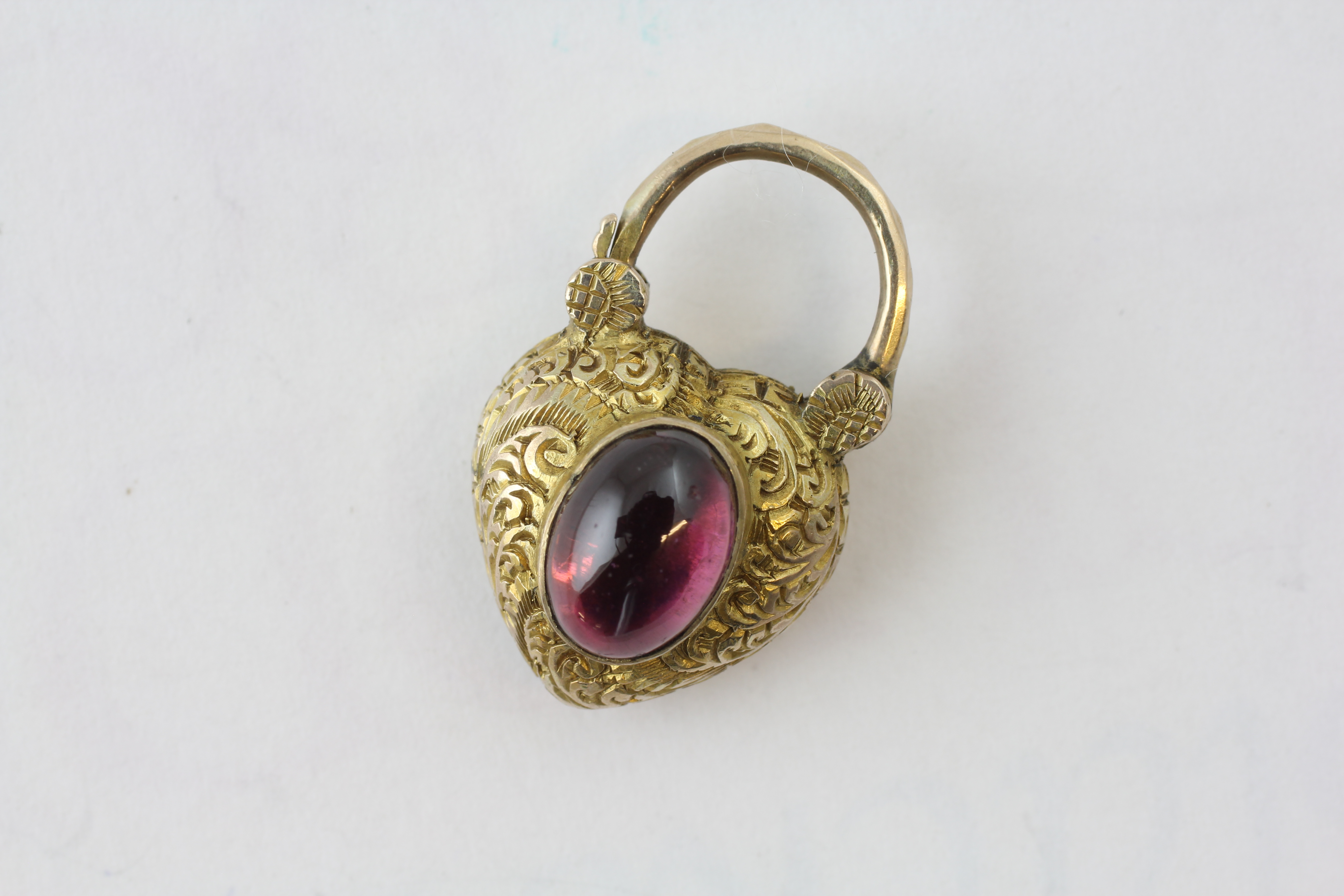 A HEART SHAPED LOCKET SET WITH AN OVAL AMETHYST CABOCHON, THE REVERSE WITH GLAZED POCKET,