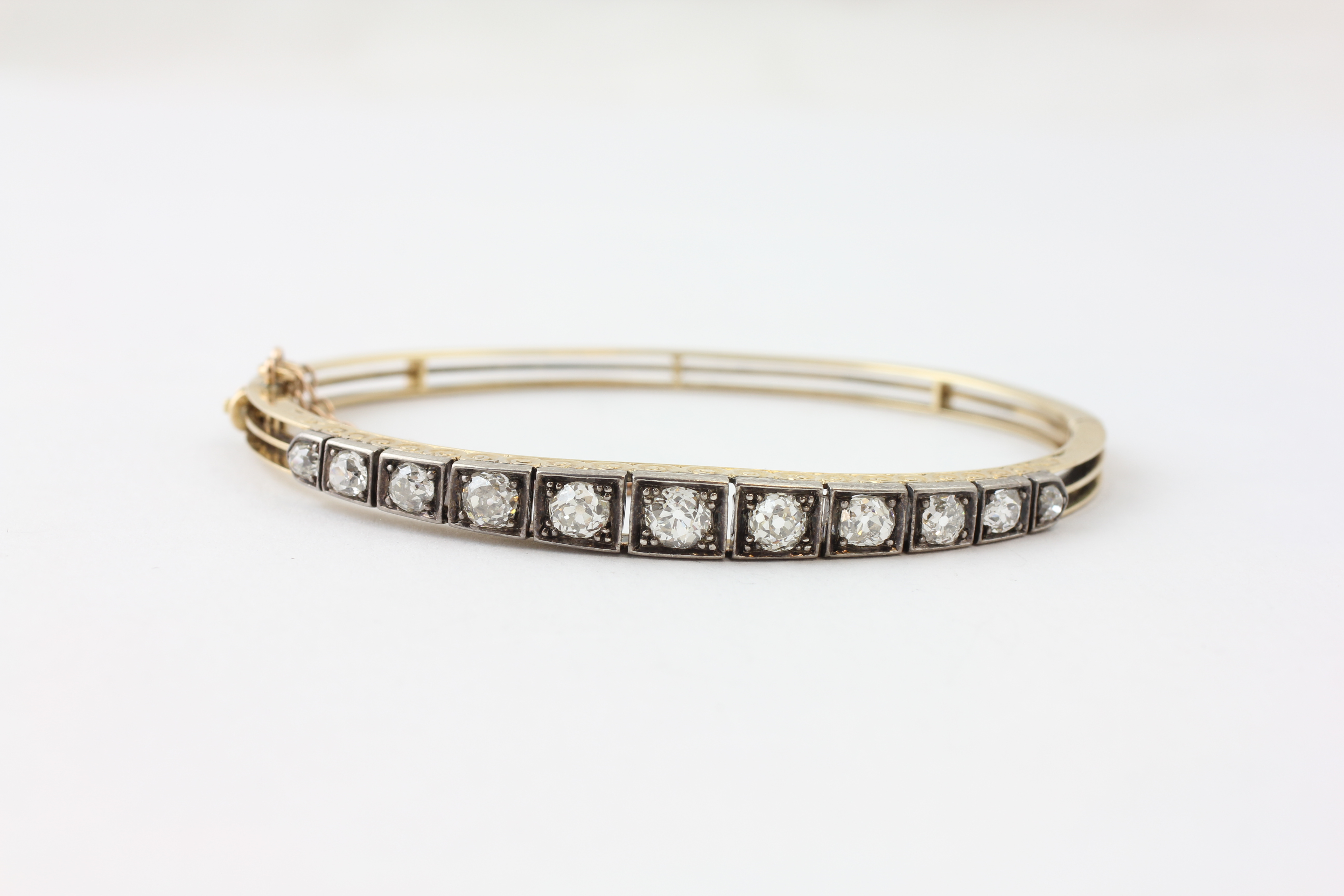 AN ELEVEN STONE DIAMOND HINGED BANGLE WITH SAFETY CHAIN, - Image 3 of 7