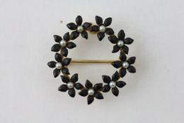 A 14CT GOLD BROOCH SET WITH FLOWERHEADS CENTRED WITH PEARLS, THE LEAVES BLACK ENAMELLED,