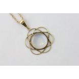 A MOONSTONE PENDANT ON AN UNMARKED YELLOW METAL CHAIN, THE CIRCULAR STONE IN A LOOPED SETTING,