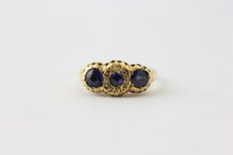 AN 18CT GOLD THREE STONE SAPPHIRE RING, THE CENTRAL STONE SURROUNDED BY DIAMOND CHIPS,