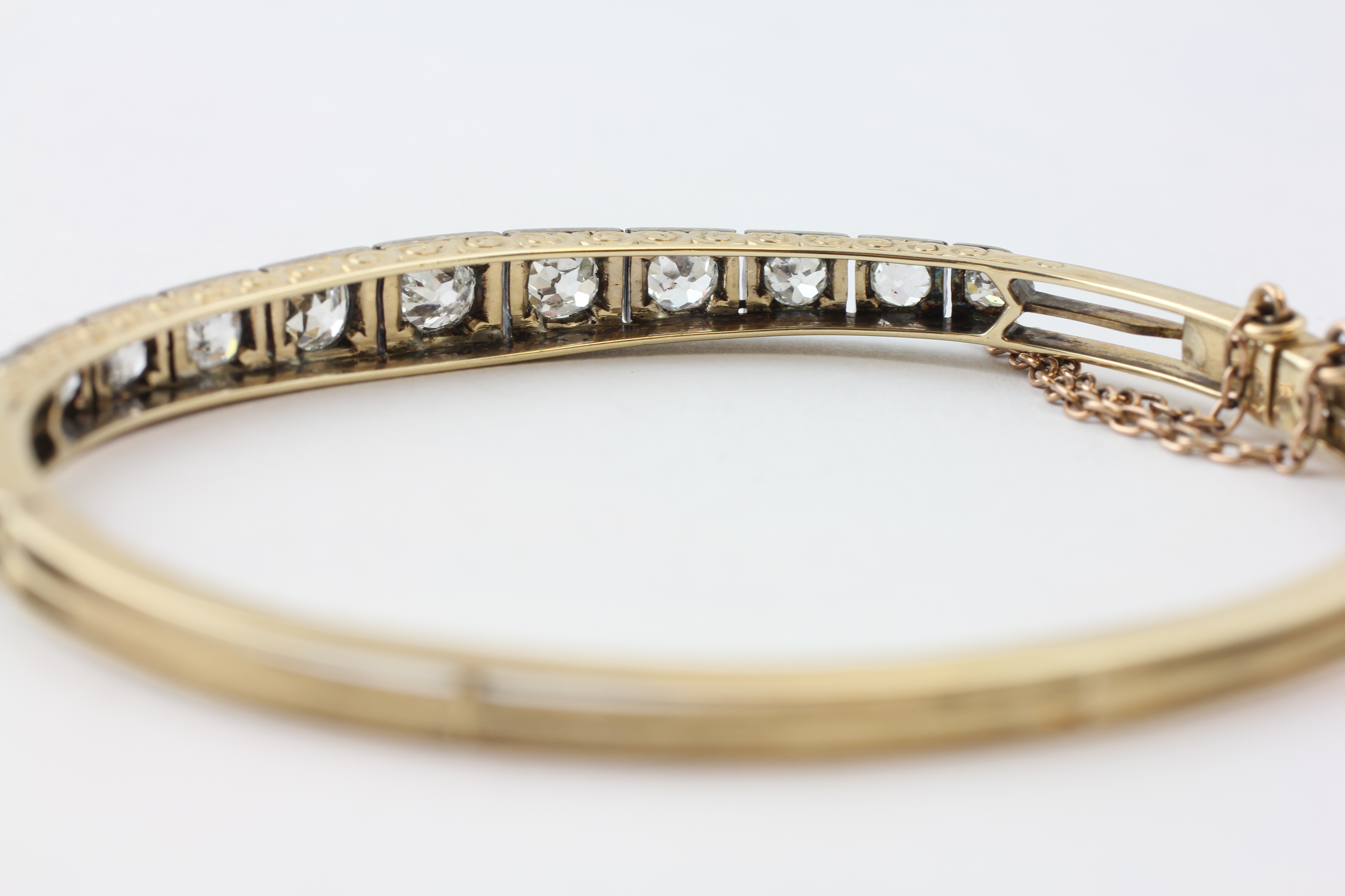 AN ELEVEN STONE DIAMOND HINGED BANGLE WITH SAFETY CHAIN, - Image 7 of 7
