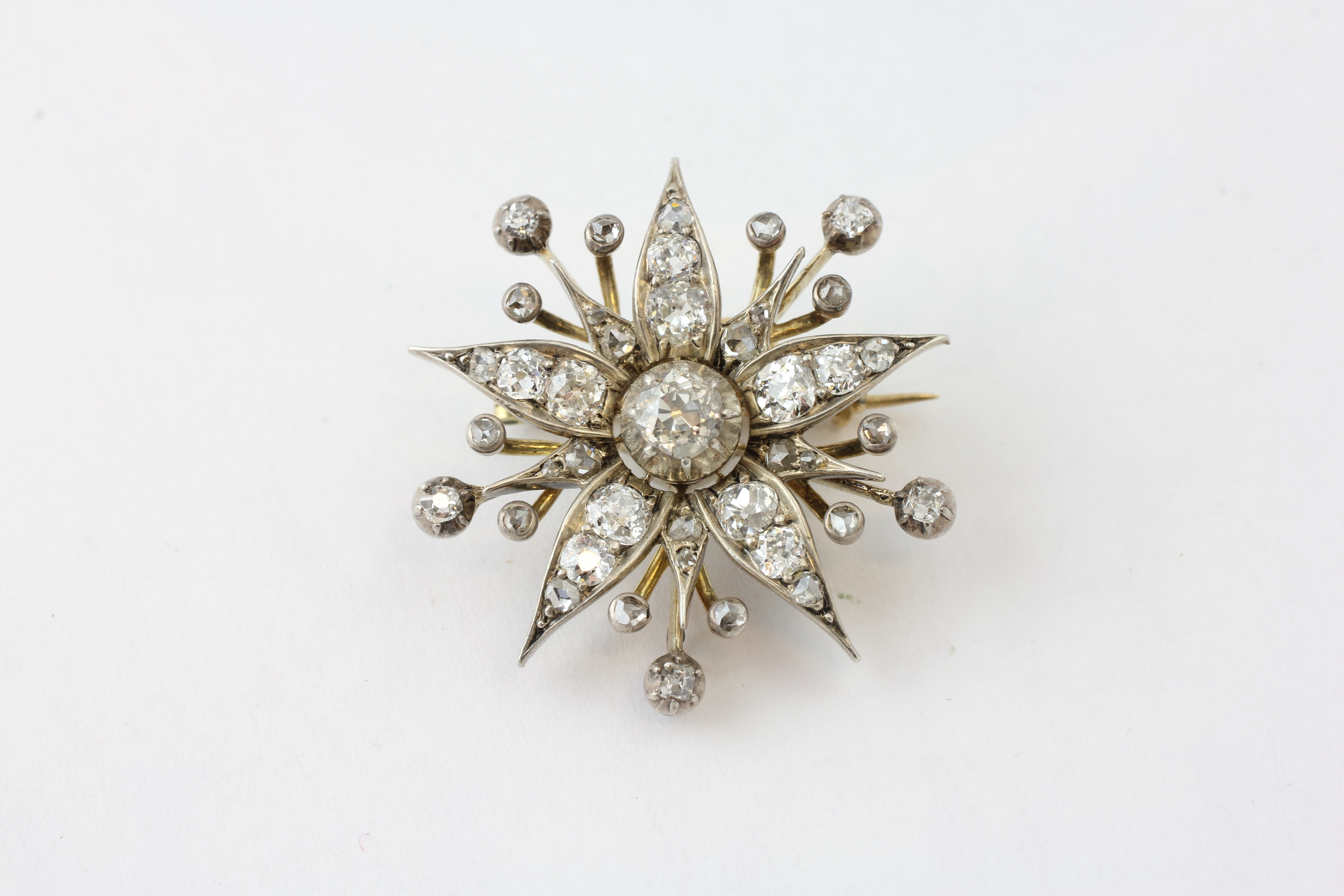 A DIAMOND BROOCH OF FLOWERHEAD FORM WITH ADJUSTMENT FOR A PENDANT, SET WITH 42 OLD CUT DIAMONDS,