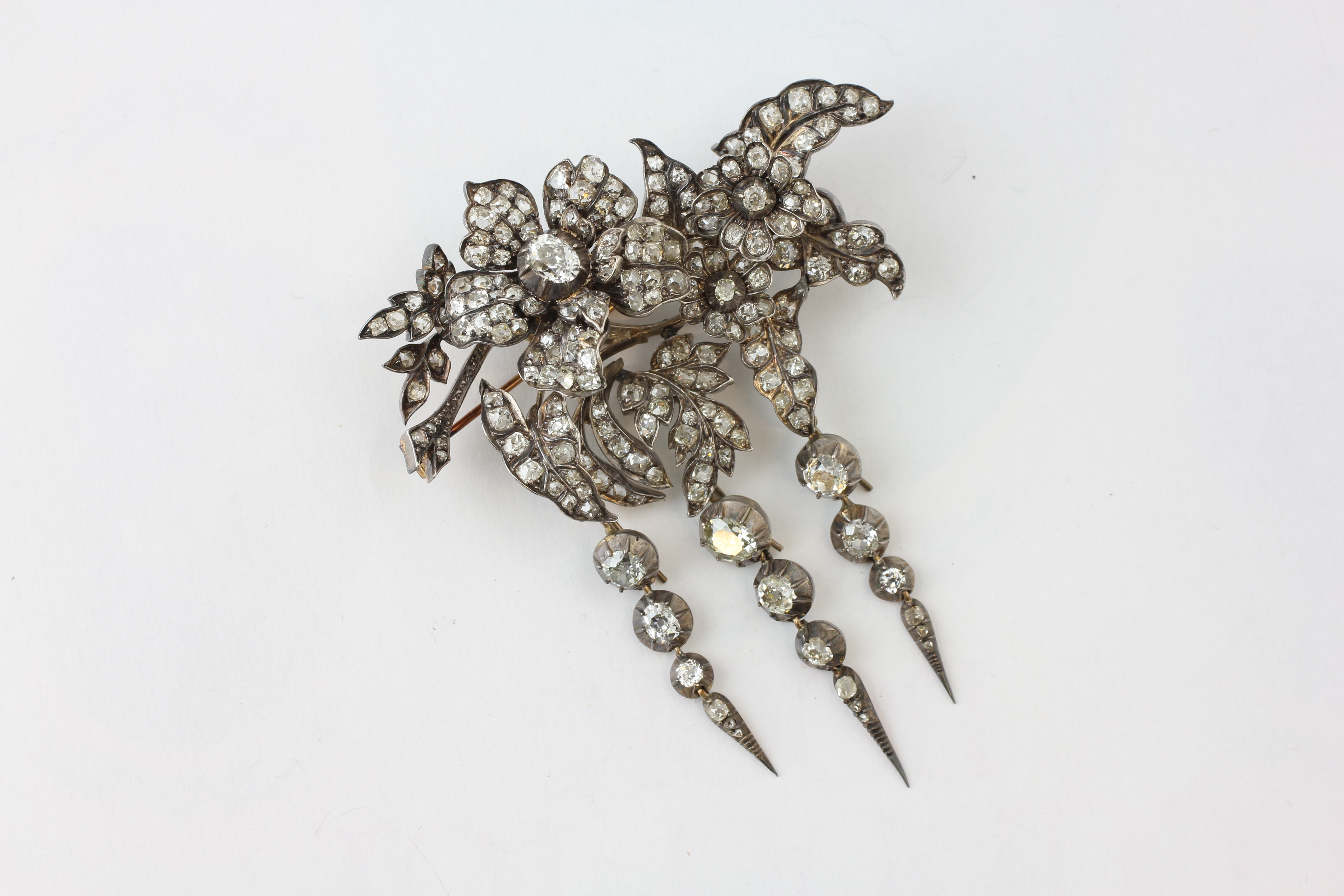 AN EDWARDIAN TREMBLANT DIAMOND BROOCH, THE PRINCIPAL OVAL CUT STONE APPROX. 6MM BY 4.