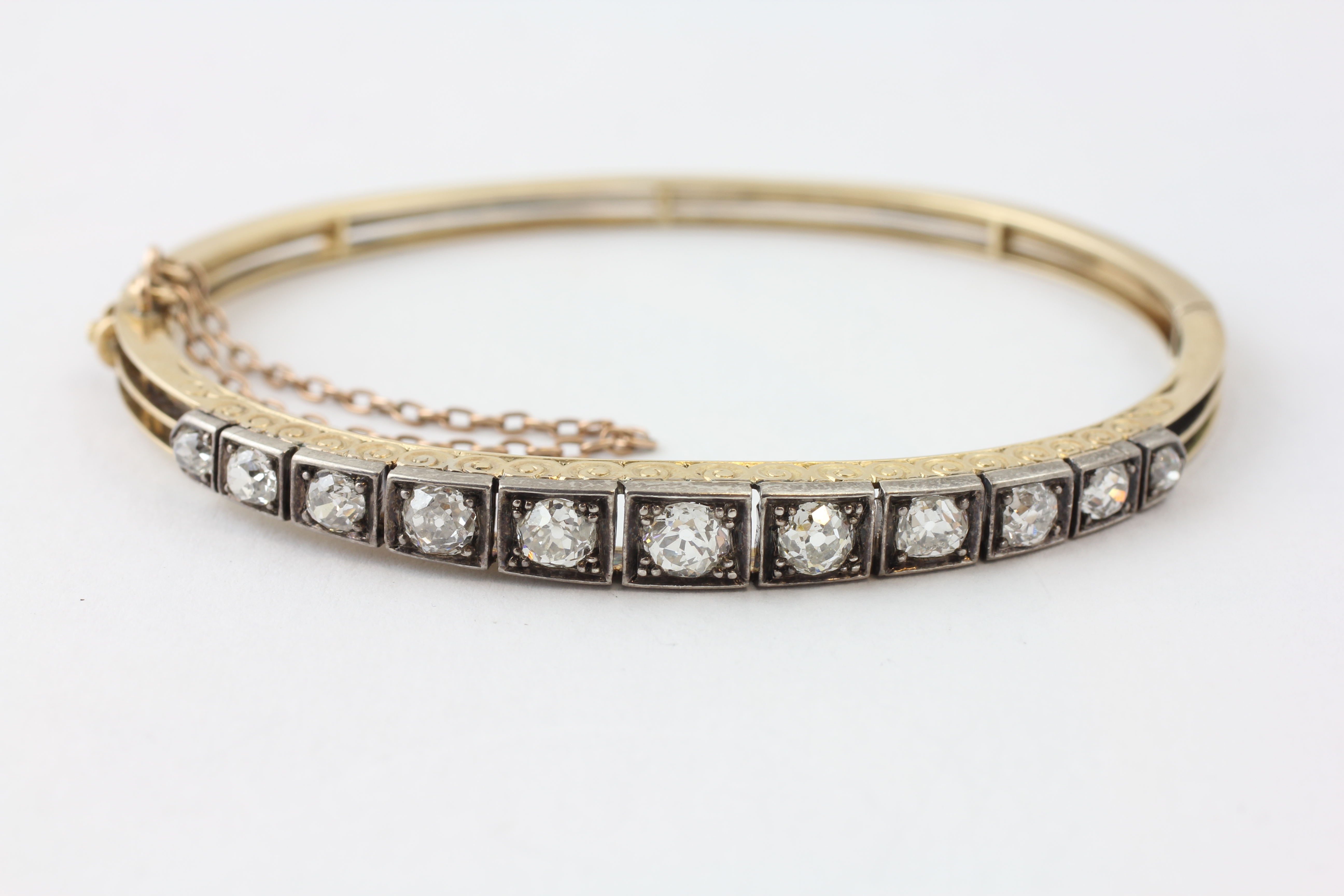 AN ELEVEN STONE DIAMOND HINGED BANGLE WITH SAFETY CHAIN, - Image 2 of 7