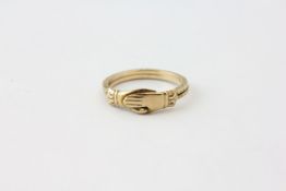 A RING OF CLASPED HAND DESIGN, MARKED 10K,