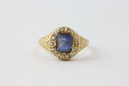 AN EDWARDIAN SAPPHIRE RING, THE RECTANGULAR STONE SURROUNDED BY SMALL DIAMONDS,