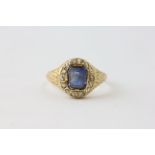 AN EDWARDIAN SAPPHIRE RING, THE RECTANGULAR STONE SURROUNDED BY SMALL DIAMONDS,