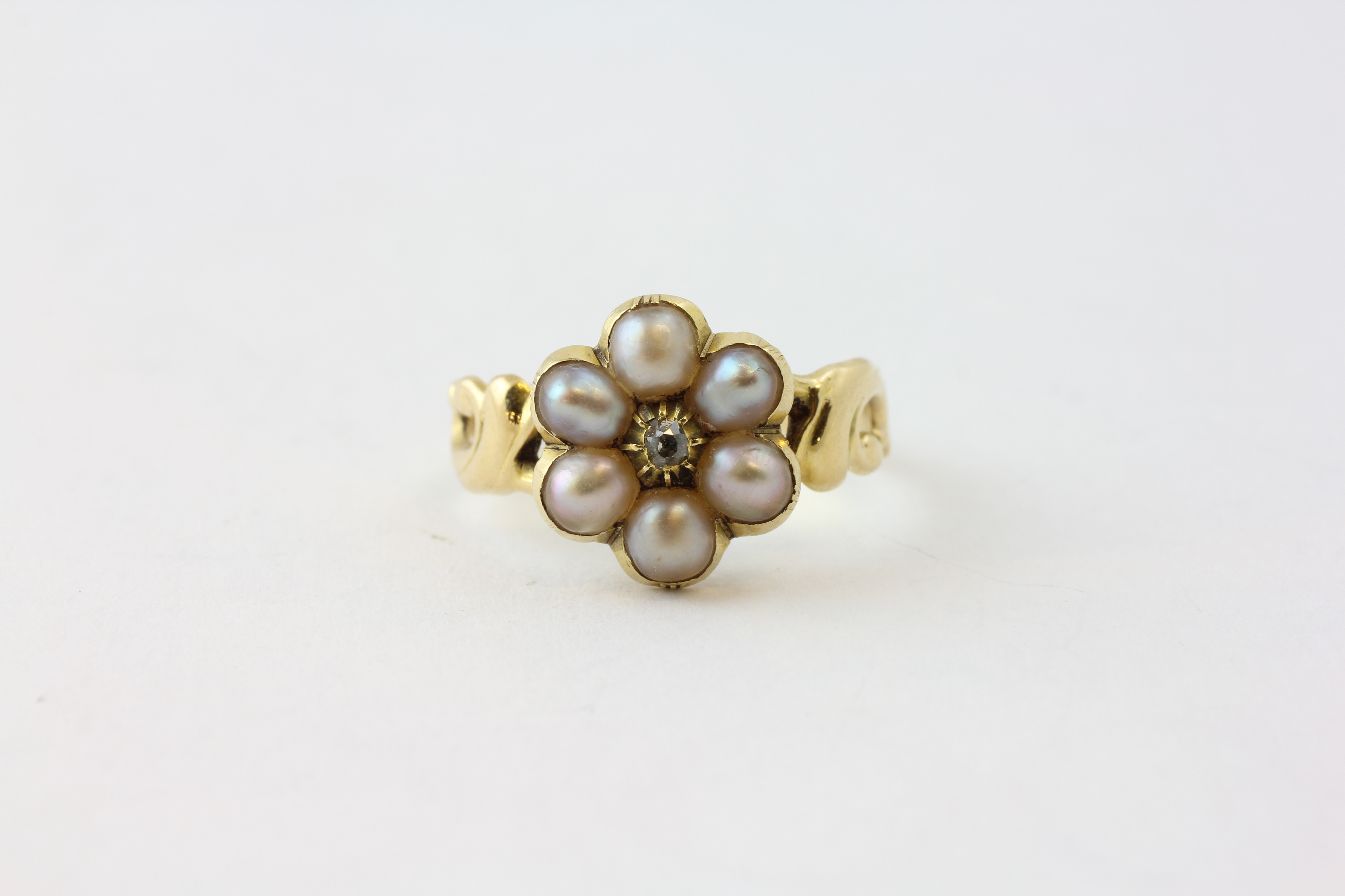 A SIX STONE PEARL RING WITH CENTRAL CLAW SET DIAMOND, THE BAND UNMARKED,