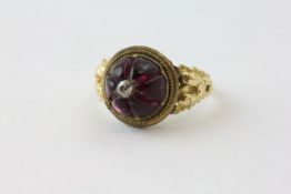 A VICTORIAN MOURNING RING, THE AMETHYST CABOCHON WITH FLUTES AND SURMOUNTED BY AN OLD CUT DIAMOND,
