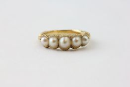 A FIVE STONE PEARL RING ON AN UNMARKED YELLOW METAL BAND(CONSIDERABLE WEAR), RING SIZE L/M,